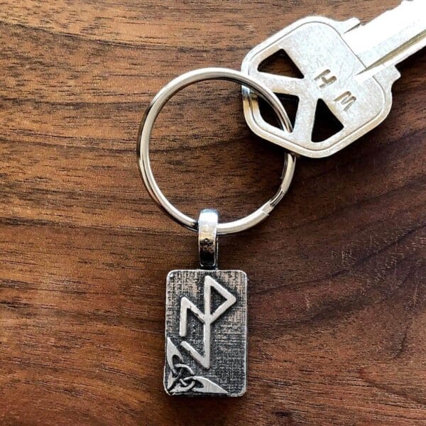 A silver keychain with a viking symbol on it.