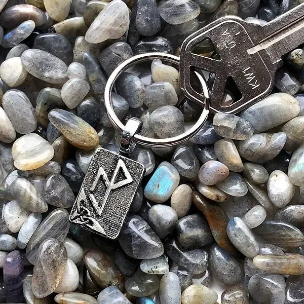 A silver keychain with a key laying on top of rocks. A silver keychain with a key laying on top of rocks.