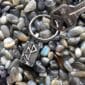 A silver keychain with a key laying on top of rocks.