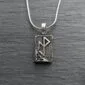 A silver pendant with a viking symbol on it.