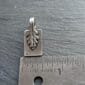 A small silver leaf charm on a ruler.