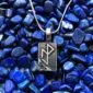 A silver pendant with a viking symbol on it.