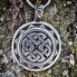 A silver pendant with a celtic design on it.