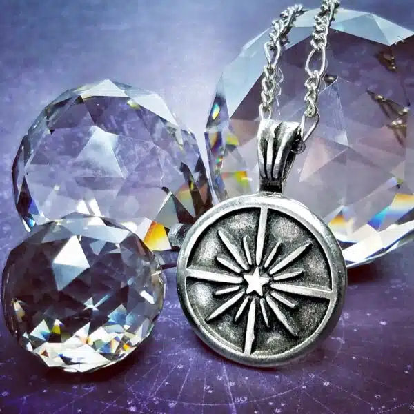 A silver compass necklace with crystals on it.