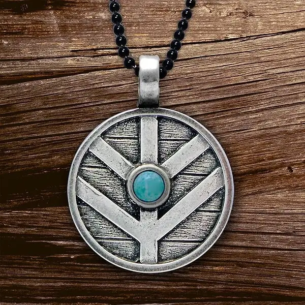 A silver pendant with a turquoise stone on it.