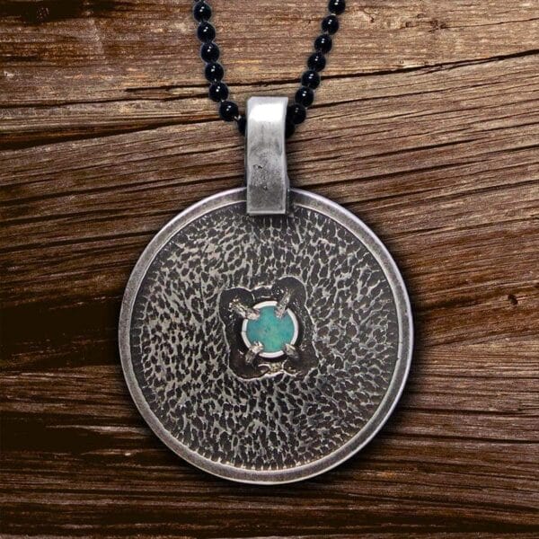 A silver pendant with a turquoise stone on it.