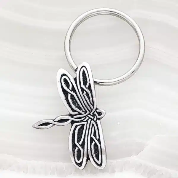 A dragonfly keychain on a white surface. A dragonfly keychain on a white surface.