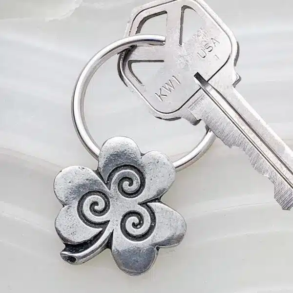 A silver key chain with a shamrock on it.