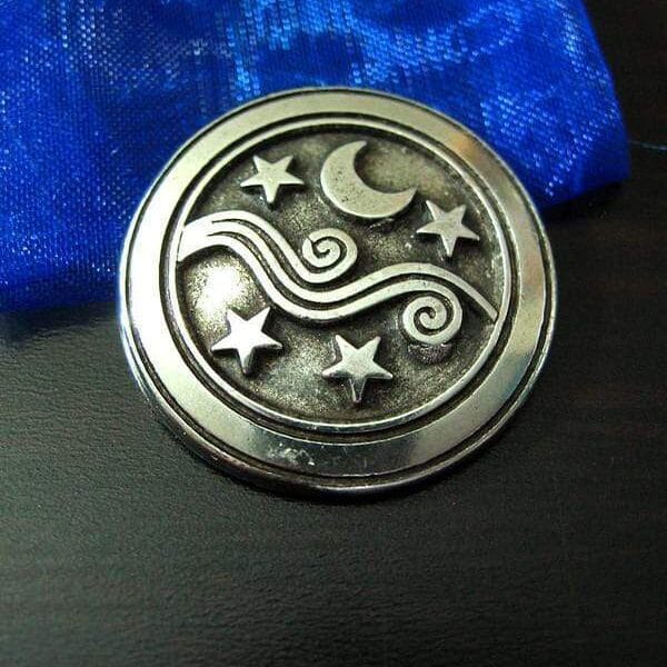 A silver medallion with a moon and stars on it.