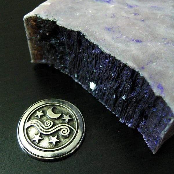 A piece of purple soap with a silver coin next to it.