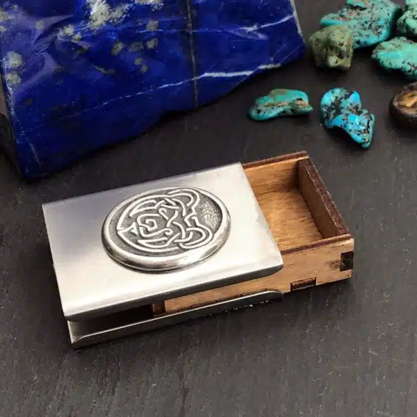 A silver business card holder with a tarot card on it.