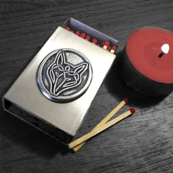 A matchbox with a red candle next to it.