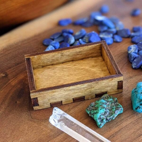 A wooden box with blue stones and a quartz crystal. A wooden box with blue stones and a quartz crystal.
