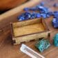 A wooden box with blue stones and a quartz crystal.
