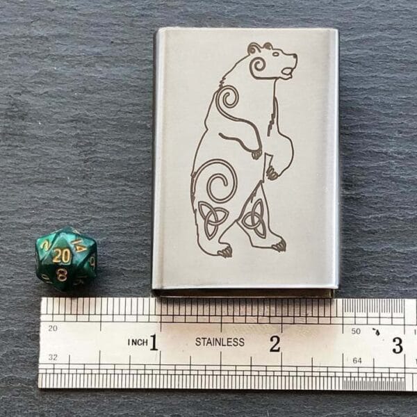 A metal tin with a bear on it and a ruler next to it.