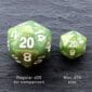 Two green d20 dice on a black surface.