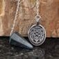 A pendant with a bear on it and a stone.