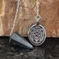 A pendant with a bear on it and a stone.