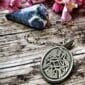 A silver pendant with a celtic design on it.