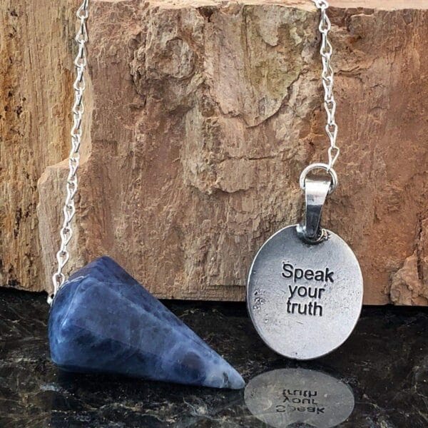A necklace with a blue stone and a pendant that says speak your truth.