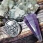 A silver pendant with a fox on it and an amethyst pendulum.