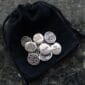 A set of silver buttons in a pouch on a table.