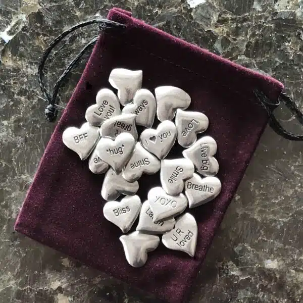 Silver heart charms in a pouch on a table. Silver heart charms in a pouch on a table.