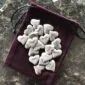 Silver heart charms in a pouch on a table.