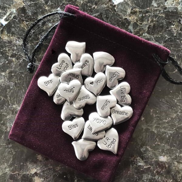 Silver heart charms in a pouch on a table.