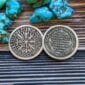 A silver coin with a viking symbol on it.