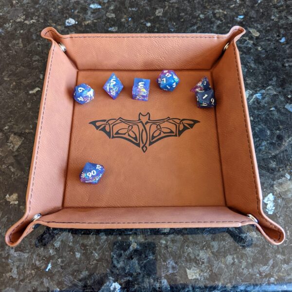 A leather dice tray with a bat design on it.