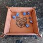 A brown leather dice tray with a bear on it.