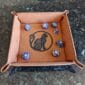 A leather tray with dice and a cat on it.