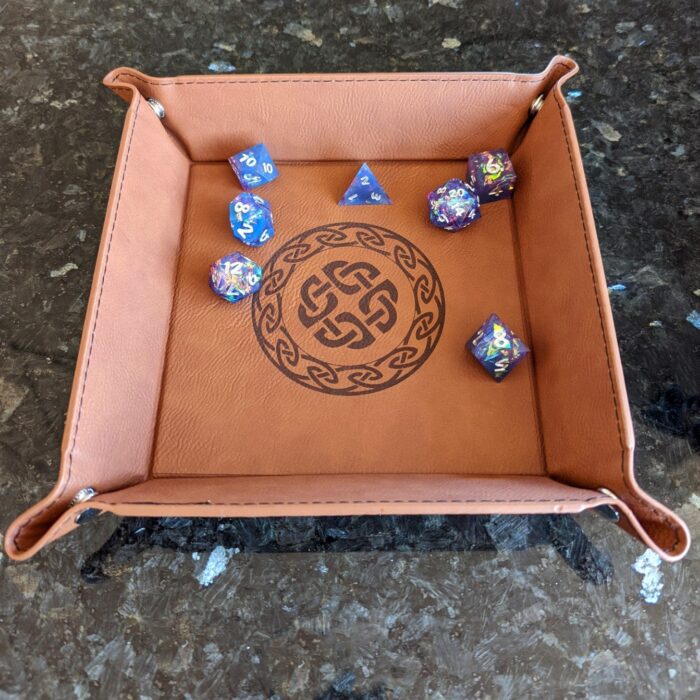 A leather dice tray with a celtic design on it.