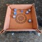 A leather dice tray with a celtic design on it.