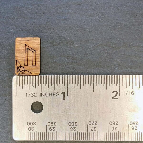 A ruler next to a wooden block with a letter on it.