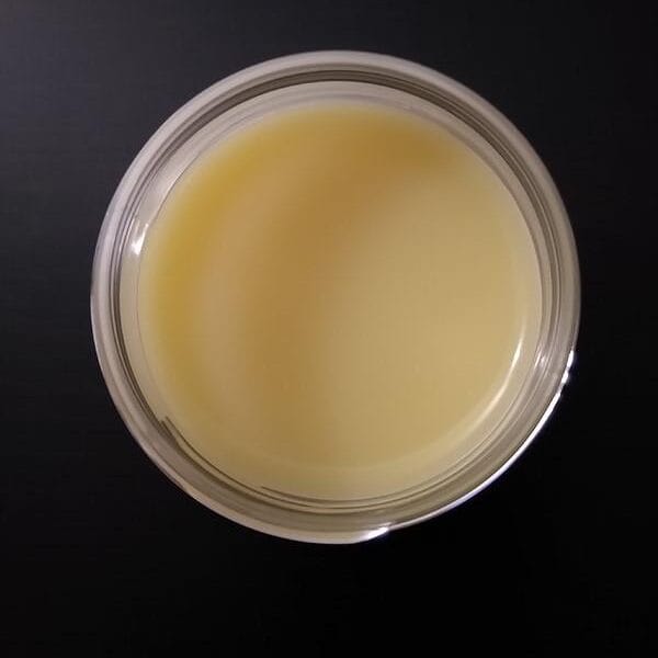 A bowl of yellow liquid on a black surface.
