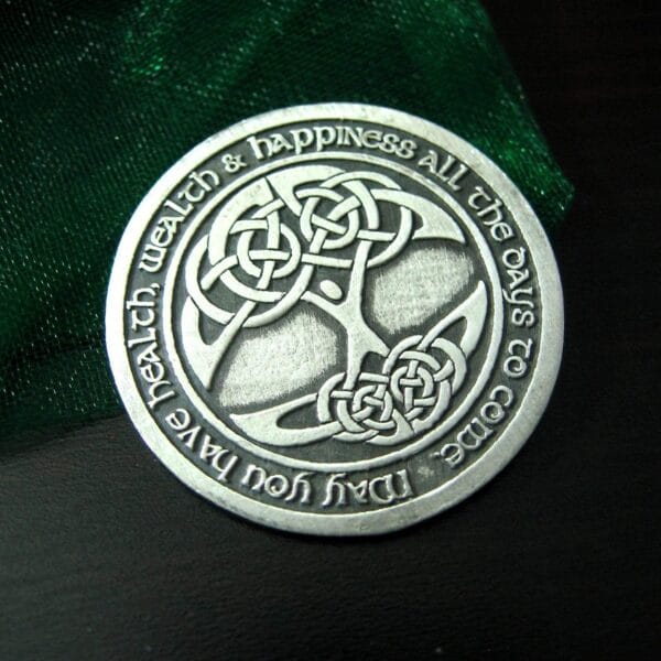 A celtic tree of life coin on a green cloth.