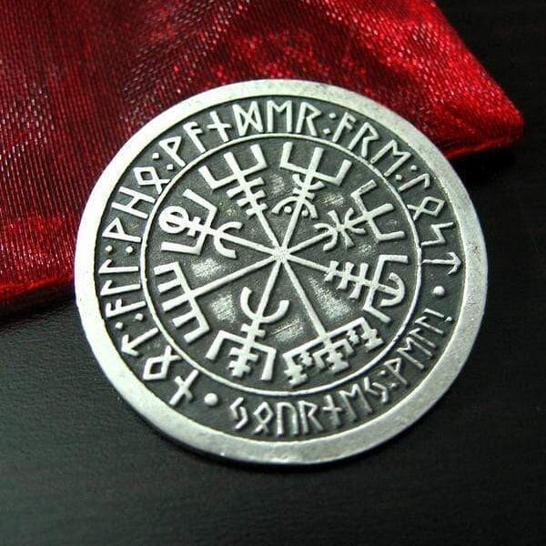 A silver coin with viking symbols on it.