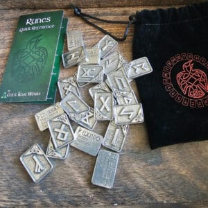 A set of Gather Rune Set 24pc Elder Futhark Pewter coins and a pouch on a table.