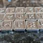 A Gather Rune Set 24pc Elder Futhark Pewter on a table.