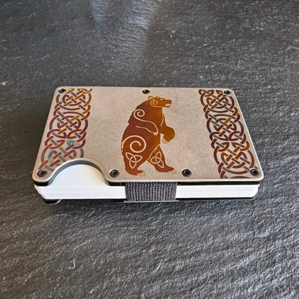 A wooden Celtic Bear Titanium Minimalist Wallet with a celtic design on it.