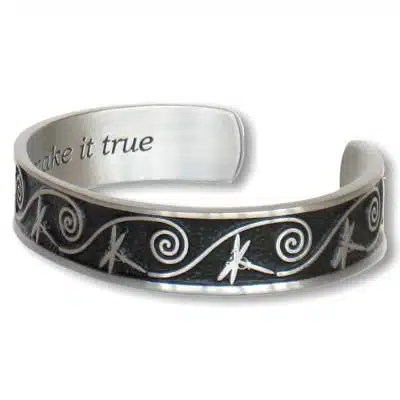 Dragonfly Dreams Bracelet Dragonfly Dreams Bracelet: A silver cuff with a black background, embellished with dragonfly and swirl designs. The inside is engraved with the text "make it true".