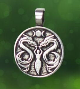 The Lady & The Dragon Dance with Fairies is a circular pendant featuring an etched design of two dragons facing a central figure holding a crescent moon, set against a green, blurred background.