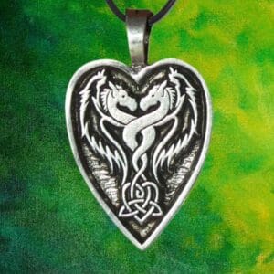 The Lady and the Dragon Act From Your Heart pendant features a heart shaped design with two intricately carved dragons facing each other in perfect symmetry, set against a blended background of green and yellow shades.