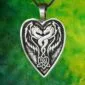 The Lady and the Dragon Act From Your Heart pendant features a heart shaped design with two intricately carved dragons facing each other in perfect symmetry, set against a blended background of green and yellow shades.