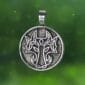 A silver pendant named "The Lady and the Dragon Be Bold" featuring a Celtic cross design, set against a backdrop of green with small light spots.