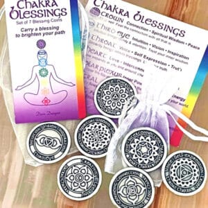 The Chakra Blessing 7 pc Oracle Set includes seven coins, each adorned with unique chakra symbols and affirmations, complete with informational cards and a pouch for display.