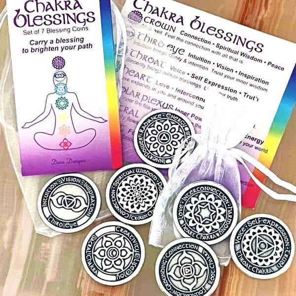 The Chakra Blessing 7 pc Oracle Set includes seven coins, each adorned with unique chakra symbols and affirmations, complete with informational cards and a pouch for display.