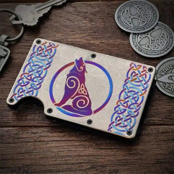 The Titanium Wolf Card Wallet, featuring a Celtic knot and stylized wolf design, sits on a wooden surface beside keys and Celtic themed coins.